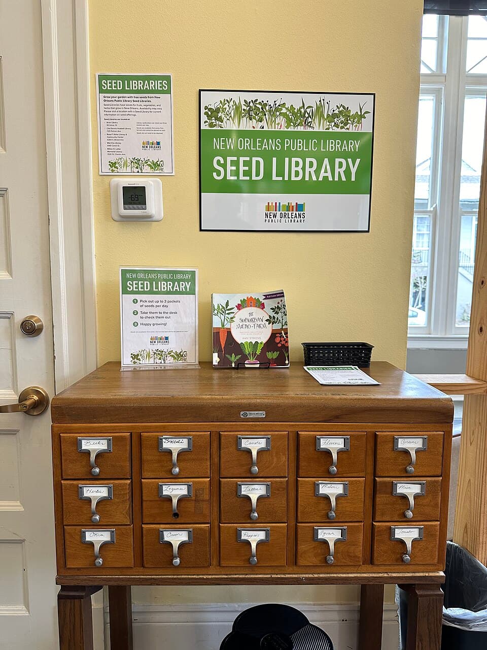 A wooden card-catalog cabinet with labelled drawers used as a seed library at a New Orleans public library