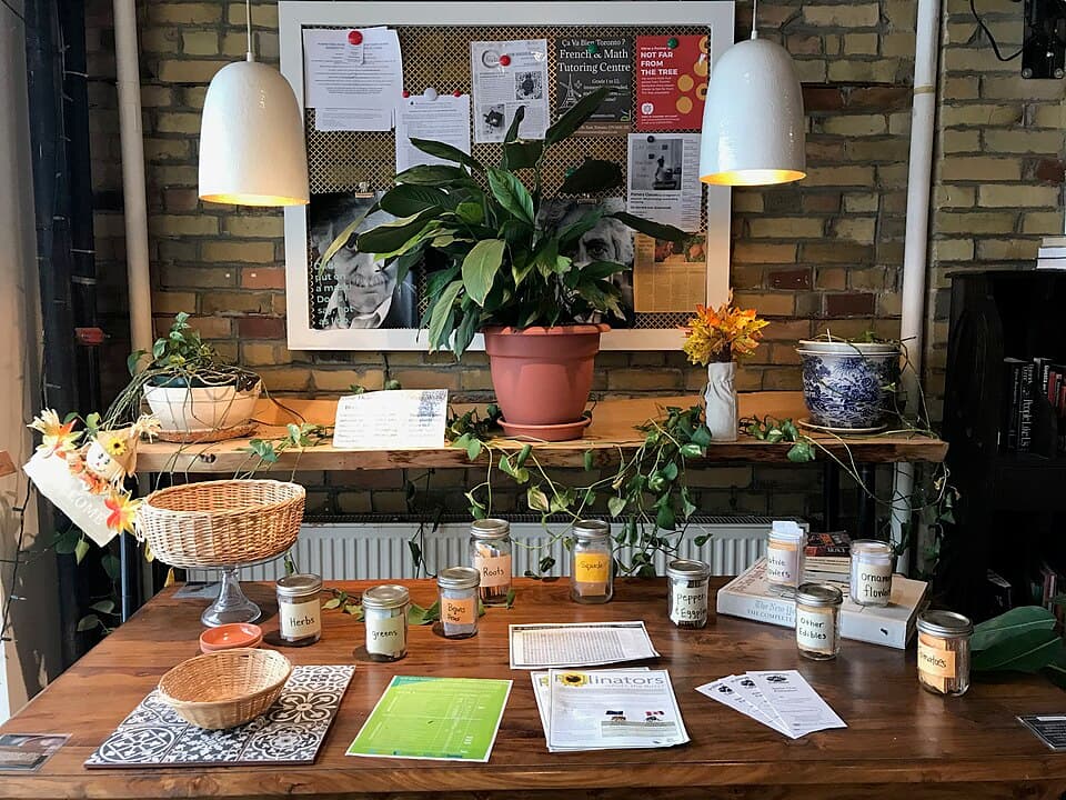 A table of labelled seed jars and handouts at the Toronto Seed Library